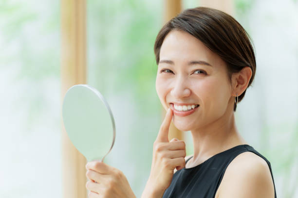 woman with short hair smiling while holding a mirror